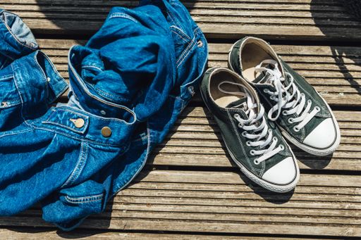 A top shot of a blue denim jacket and sneakers on a wooden dock