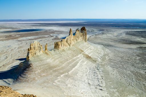 Aerial view of the stunning Bozzhira Canyon in Kazakhstan's Ustyurt Plateau, showcasing dramatic rock formations under a clear sky.