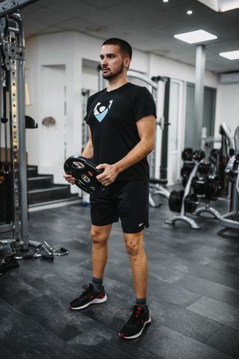 A young handsome male in sportswear working out in a gym