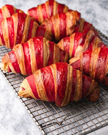 A vertical shot of delicious raspberry croissants on a net tray on the table