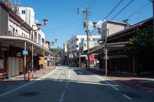 A quiet street in a Japanese town with traditional architecture and clear blue sky.