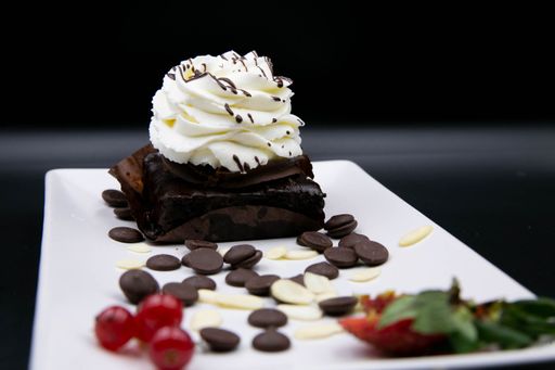 A selective focus shot of a brownie with whipped cream on a decorated plate