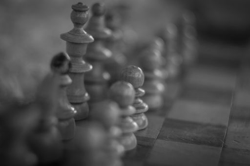 A grayscale shot of chess pieces assembled on the board