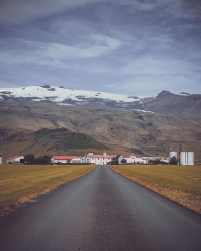 A vertical shot of a road leading to buildings near the Eyjafjallajokull in Iceland