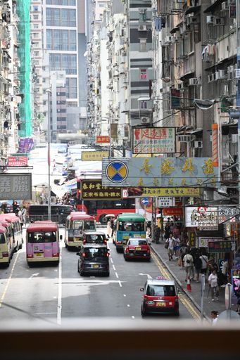 Bustling Hong Kong street scene with taxis, buses, and pedestrians amidst tall buildings and vibrant signs.