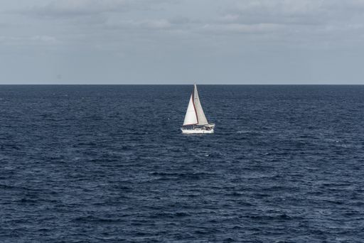 A white sailboat sailing alone across the open Mediterranean sea in daytime