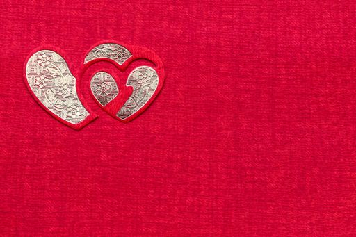 A closeup of a heart-shaped pattern on a pink burlap surface with copy space