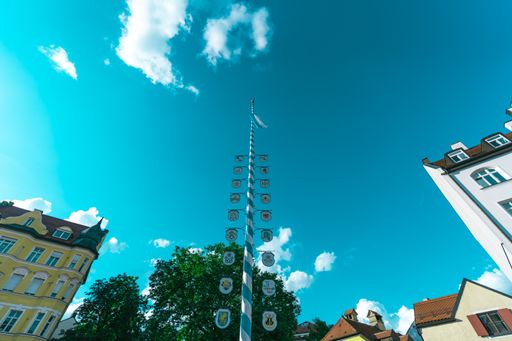 A low angle shot of a beautiful maypole in Munich, Germany under the vibrant blue cloudy sky