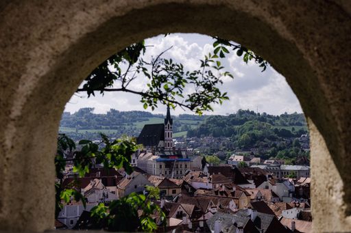 Scenic view of Cesky Krumlov's rooftops framed by an arch with hills