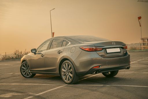 A sleek gray sedan parked in an empty lot during a golden sunset, showcasing modern automotive design.