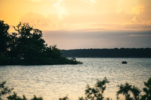 A scenic view of a small boat sailing on a calm lake during a beautiful sunset