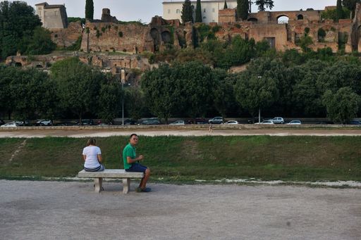A couple of tourists sitting on a bench in a park near Circus Maximus in Rome, Italy