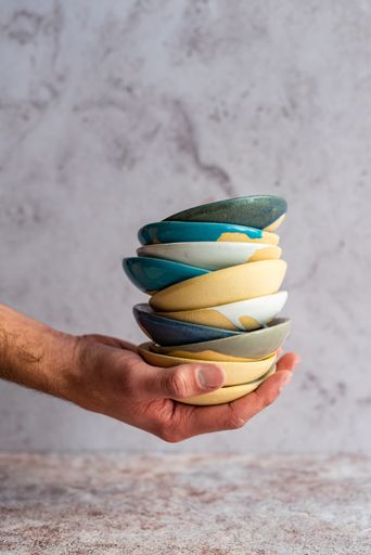A hand holding a stack of glazed ceramic bowls