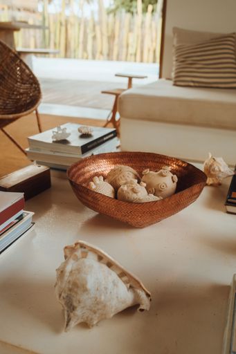 Cozy living room with white couch, wicker chair, and coffee table with books and seashells.