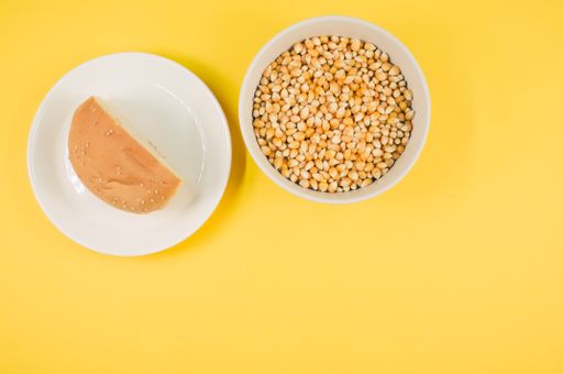 A top view of half bread bun and corn grains on a plate isolated on yellow background