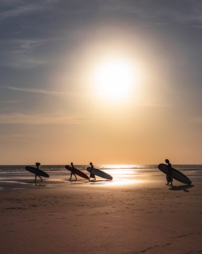 A scenic view of four surfers on the beach in Bali, Indonesia