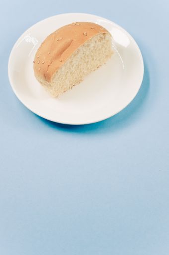 A vertical shot of half bread bun on a plate isolated on blue background