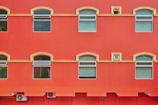 Salmon-colored hotel facade with symmetrical windows and balconies