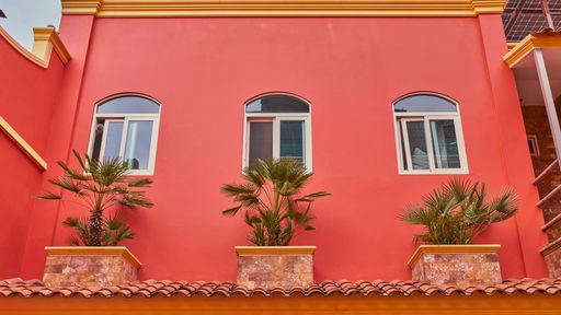 Salmon-colored hotel facade with symmetrical windows and balconies