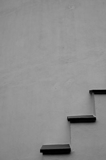 A monochrome shot of a side view of a stone staircase against the wall