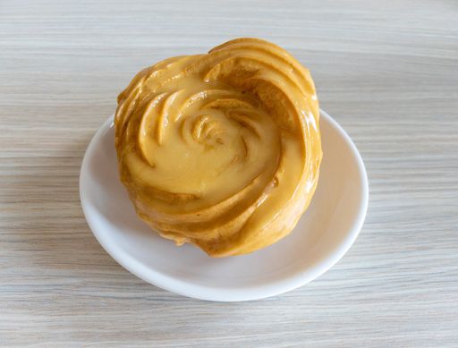 A top view of a tasty eclair with yellow cream on top of it on a wooden table