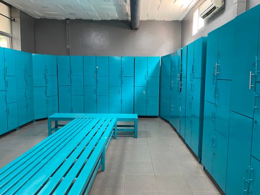 An empty dressing room with blue lockers and blue benches