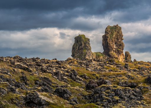 Dramatic rock formations under a cloudy sky in a rugged landscape, showcasing natural beauty and geological features.