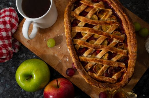 A high angle shot of fresh homemade apple pie and a cup of coffee on a wooden surface