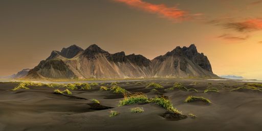 Stunning view of Vestrahorn mountain with black sand dunes and vibrant sky at sunset in Iceland.