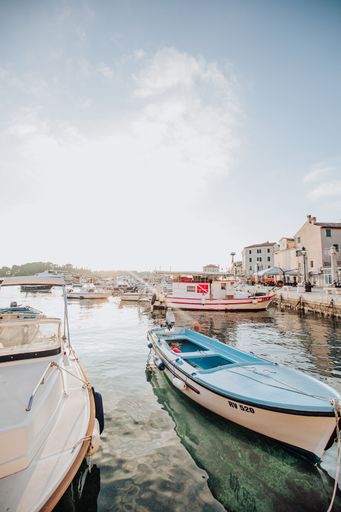 Scenic view of a marina with boats docked under a bright sky in Rovinj, Croatia, capturing the tranquil atmosphere of the harbor.