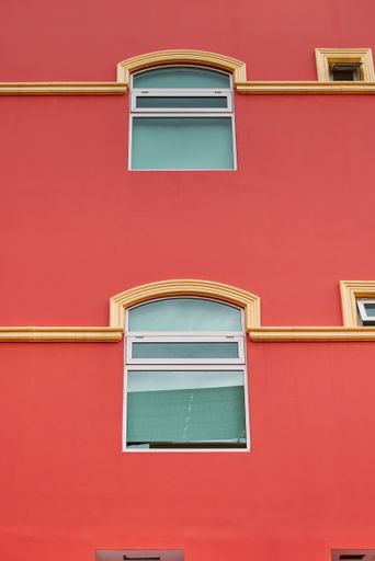 Salmon-colored hotel facade with symmetrical windows and balconies