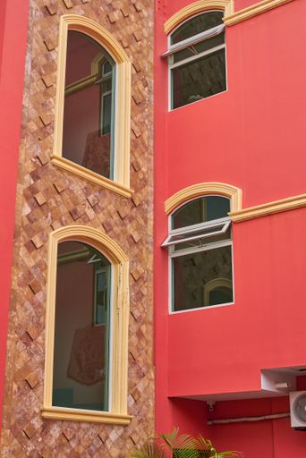 Salmon-colored hotel facade with symmetrical windows and balconies