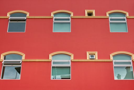 Salmon-colored hotel facade with symmetrical windows and balconies