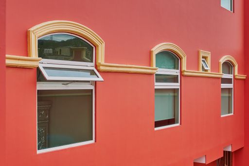 Salmon-colored hotel facade with symmetrical windows and balconies