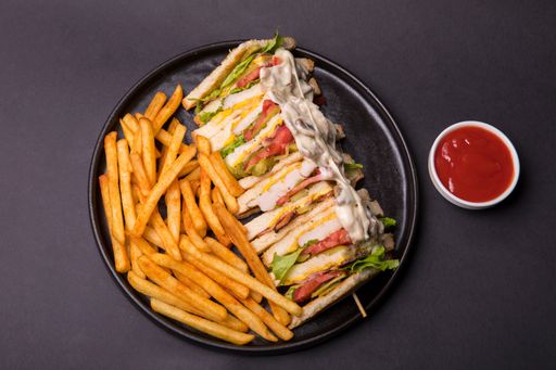 A top view of club sandwich with French fries served with ketchup sauce