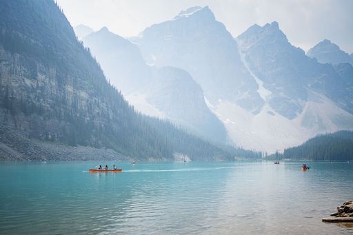 Scenic view of canoeists on Moraine Lake with majestic mountains in Banff National Park, Alberta, Canada.