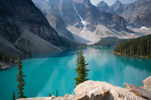 Scenic view of Moraine Lake with turquoise waters surrounded by mountains and pine trees in Banff National Park, Alberta, Canada.