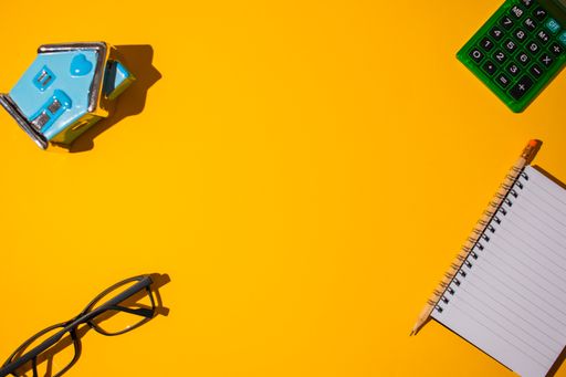 A top view of a beautiful neon orange surface with stationery objects at the corner
