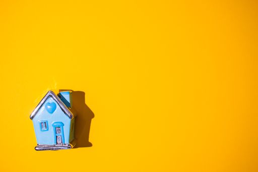 A top view of a vibrant orange surface with a small ceramic house toy on it