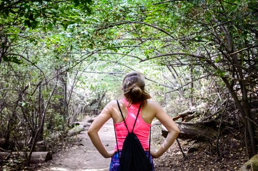 A rear view of a sexy hiker woman with a drawstring bag along the forest