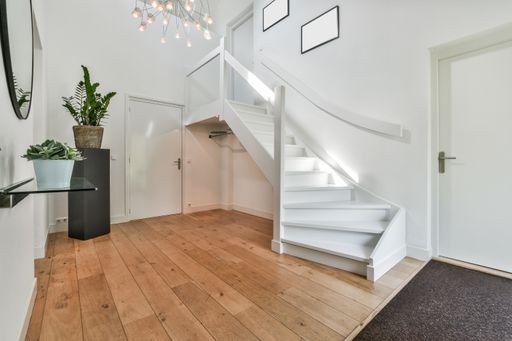 A room with the furniture in it and the bright light coming from the window