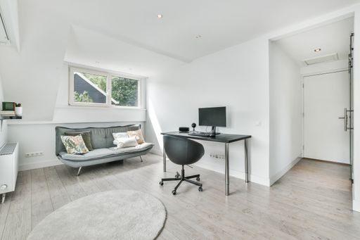 A house office room in white and gray colors with a desk and sofa