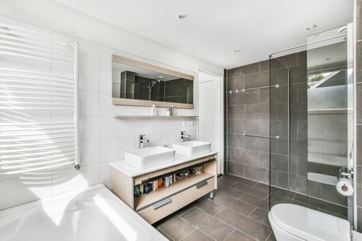 A room with the furniture in it and the bright light coming from the window