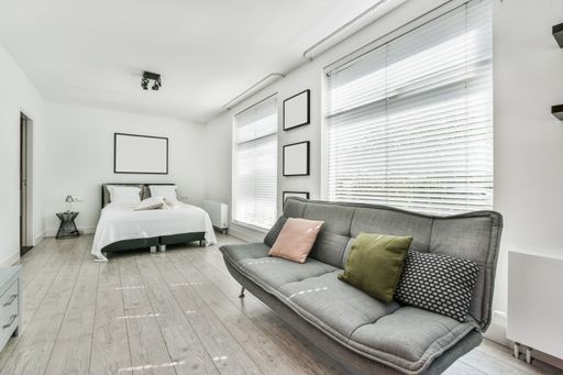 A room with the furniture in it and the bright light coming from the window