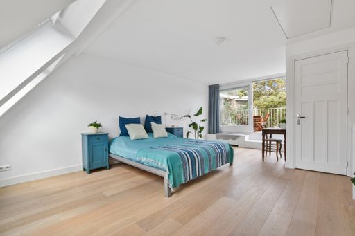 A modern bedroom with a wooden floor, white walls, and blue bedding