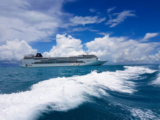 The beautiful waves of the Caribbean sea with a cruise ship on it during daylight