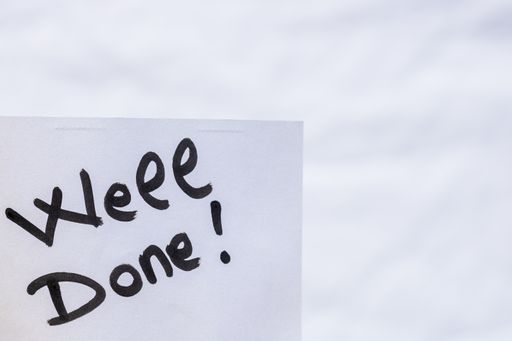 A handwriting text saying 'well done' on a white paper