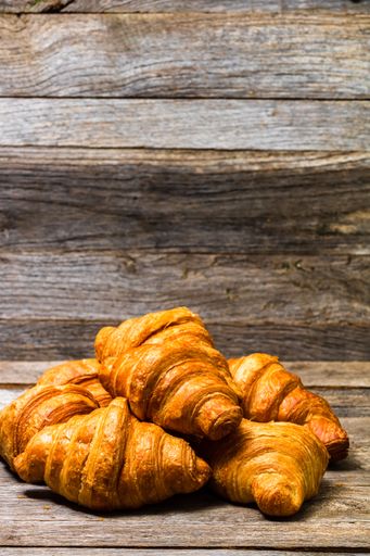 A closeup shot of delicious freshly baked croissants isolated on wooden board