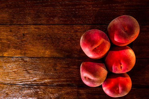 A top view of fresh juicy peaches on rustic wooden table
