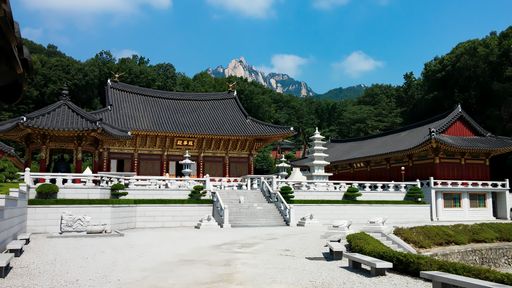 Buddhist temple with front yard, bell, benches at Bukhansan National Park in Seoul, South Korea, blue sky during summer